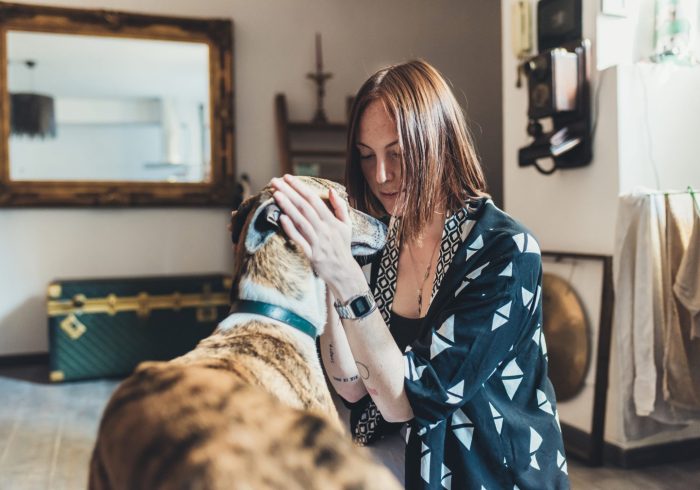 arthritis in dog - Young woman petting her dog in apartment